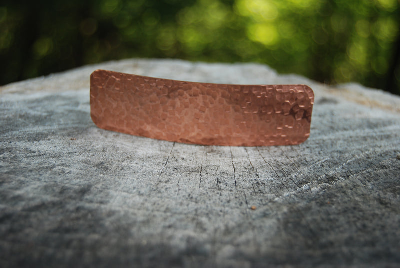 Copper hammered metal object on wood